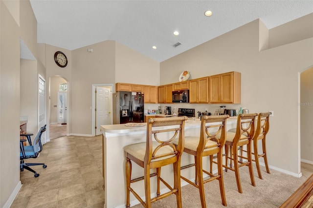4078 Waltham Forest Dr, Tavares, FL 32778 - kitchen with kitchen peninsula, high vaulted ceiling, a breakfast bar area, and black appliances