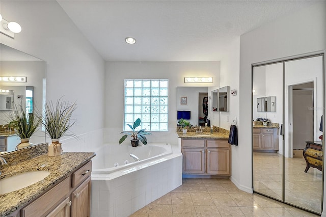 bathroom with vanity, tile patterned floors, and tiled bath