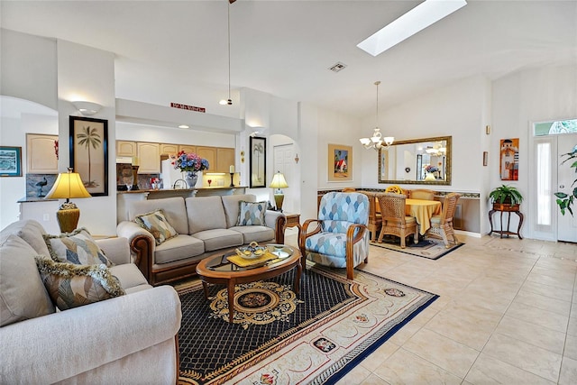 tiled living room featuring high vaulted ceiling, a chandelier, and a skylight