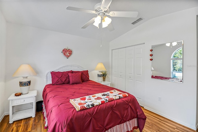 bedroom with hardwood / wood-style flooring, vaulted ceiling, ceiling fan, and a closet