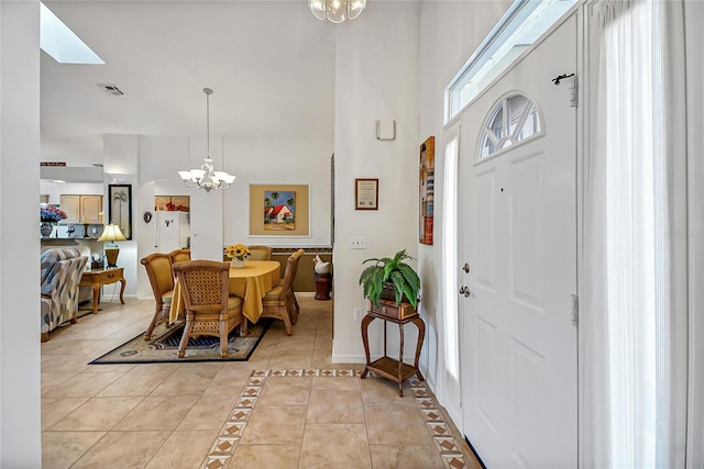 entrance foyer with a chandelier, a high ceiling, and light tile patterned floors