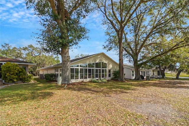 rear view of property featuring a sunroom and a lawn