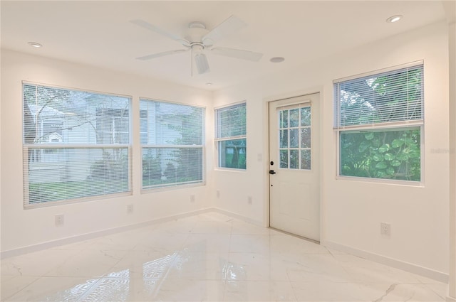 unfurnished sunroom with ceiling fan