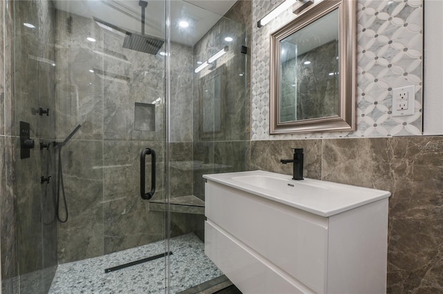 bathroom with a shower stall, tile walls, and vanity