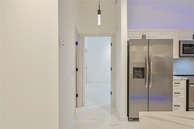 kitchen with baseboards, stainless steel appliances, decorative backsplash, white cabinetry, and marble finish floor