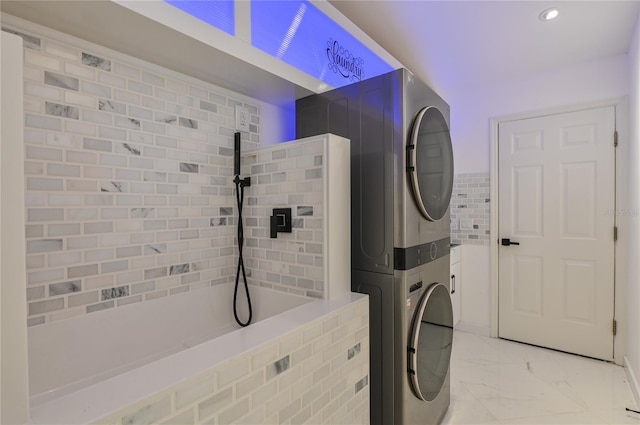 washroom with tile walls, marble finish floor, laundry area, and stacked washing maching and dryer