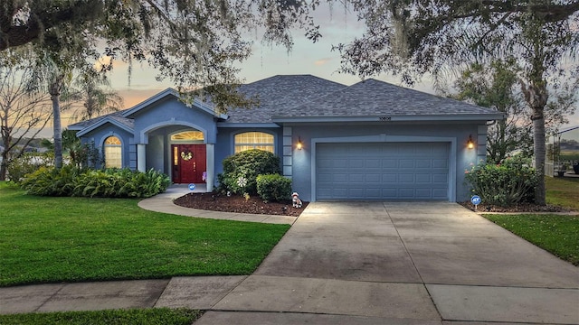 single story home with a garage and a lawn