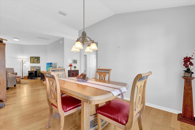 dining space with a notable chandelier, vaulted ceiling, and light hardwood / wood-style floors