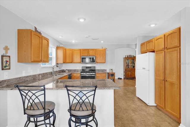 kitchen featuring stainless steel appliances, a kitchen bar, and kitchen peninsula