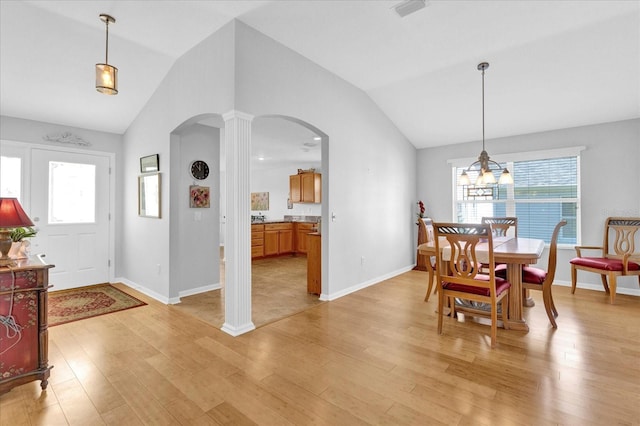 dining area featuring lofted ceiling, light hardwood / wood-style flooring, and decorative columns