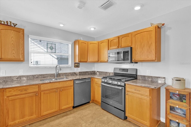 kitchen with light stone countertops, appliances with stainless steel finishes, and sink