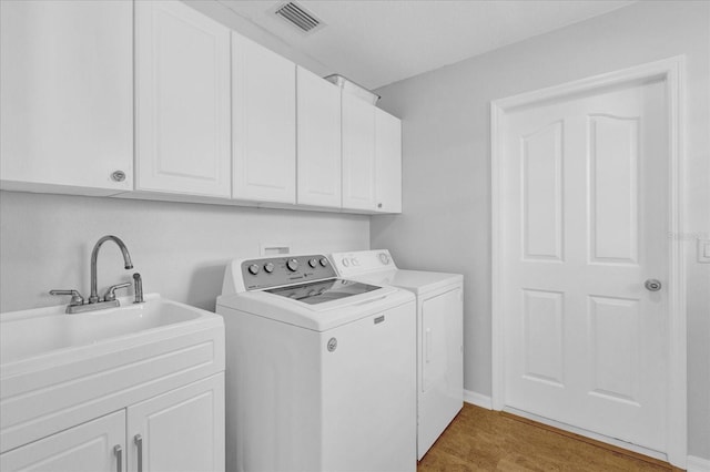 clothes washing area with cabinets, independent washer and dryer, and light hardwood / wood-style floors