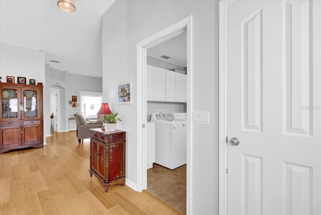 hallway with separate washer and dryer and light hardwood / wood-style floors