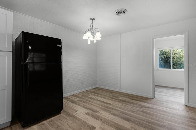 dining room featuring visible vents, a textured ceiling, brick wall, a chandelier, and light wood-type flooring