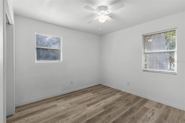 unfurnished room with baseboards, a textured ceiling, light wood-style flooring, and a ceiling fan