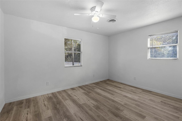 empty room featuring light wood-style flooring, visible vents, and baseboards