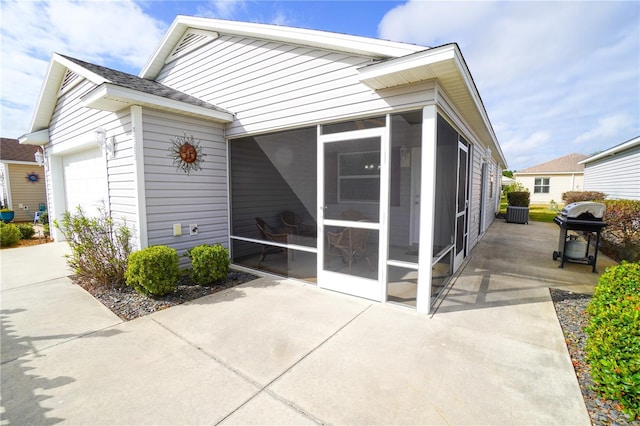 view of property exterior with a patio, a sunroom, and a garage