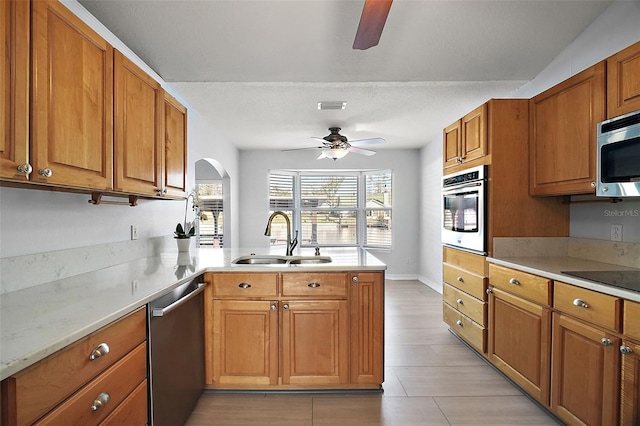 kitchen featuring stainless steel appliances, a peninsula, a sink, visible vents, and brown cabinetry