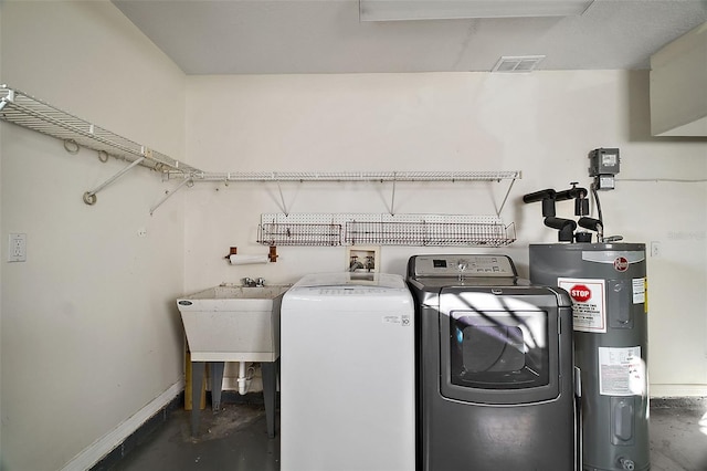 clothes washing area featuring laundry area, visible vents, baseboards, electric water heater, and washer and dryer