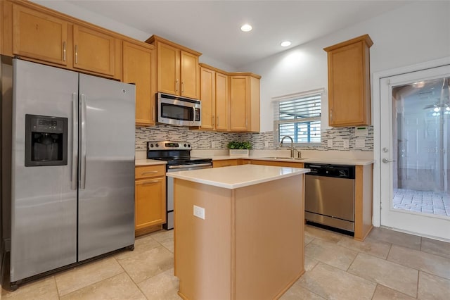 kitchen with appliances with stainless steel finishes, sink, backsplash, a center island, and light brown cabinets