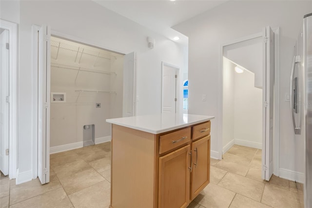 kitchen featuring light tile patterned floors, stainless steel fridge, and a kitchen island