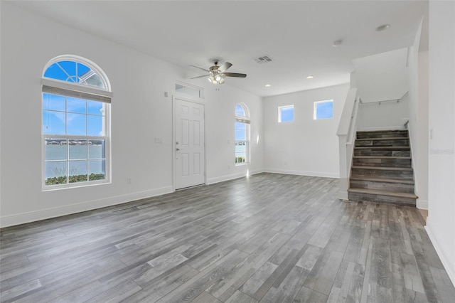 unfurnished living room featuring a water view, ceiling fan, and light wood-type flooring