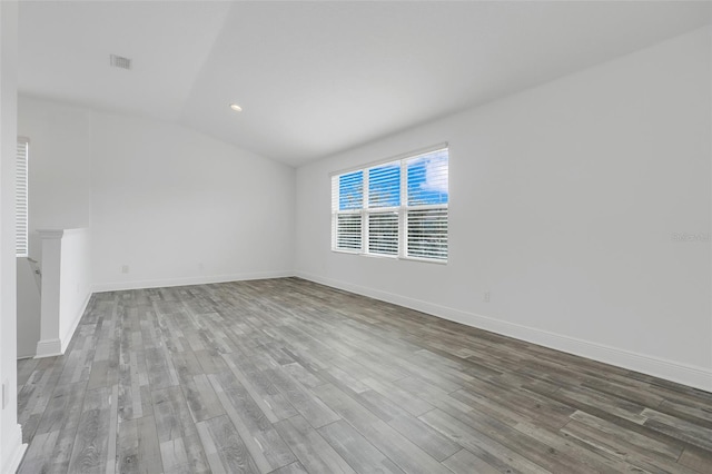 spare room with hardwood / wood-style flooring and vaulted ceiling