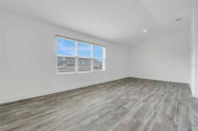 empty room with light hardwood / wood-style flooring and vaulted ceiling