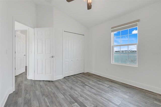 unfurnished bedroom featuring ceiling fan, lofted ceiling, light hardwood / wood-style floors, and a closet