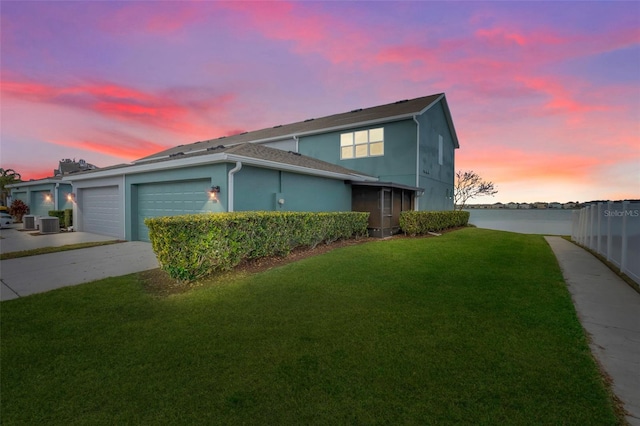 property exterior at dusk featuring a garage and a yard