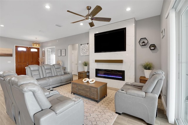 living room featuring ceiling fan, a high end fireplace, and light hardwood / wood-style flooring