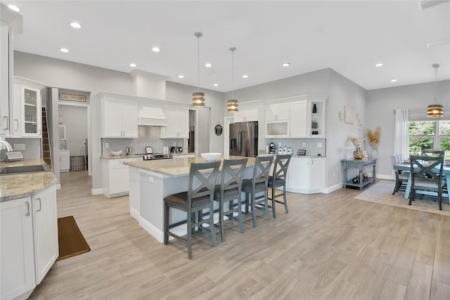 kitchen featuring hanging light fixtures, light stone countertops, white cabinets, and appliances with stainless steel finishes