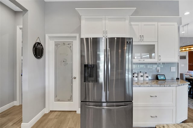 kitchen featuring stainless steel refrigerator with ice dispenser, white cabinetry, light stone counters, and light wood-type flooring