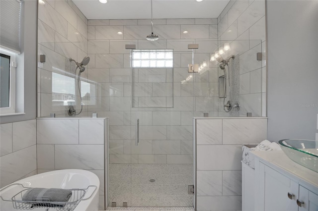 bathroom with vanity, shower with separate bathtub, and tile walls