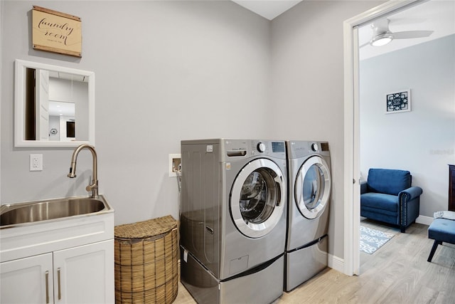 laundry area with sink, cabinets, washing machine and clothes dryer, ceiling fan, and light hardwood / wood-style flooring