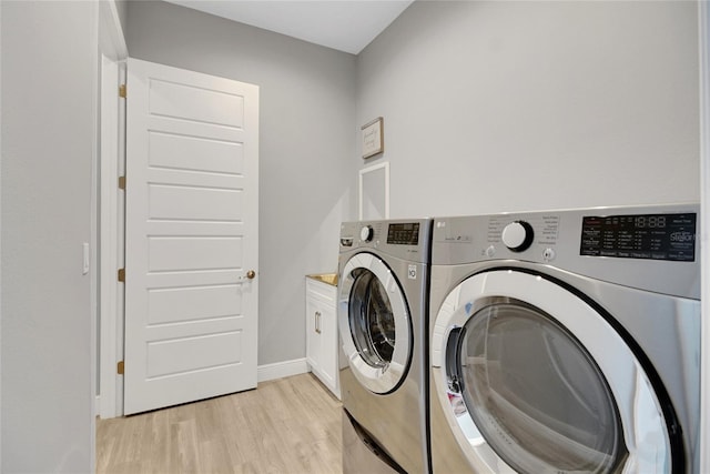 laundry room featuring cabinets, washer and dryer, and light wood-type flooring