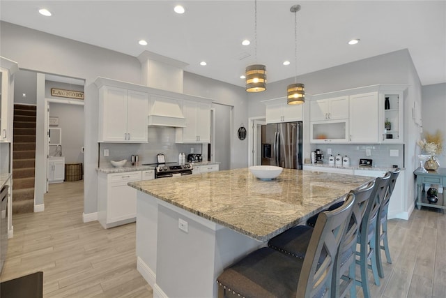 kitchen featuring hanging light fixtures, white cabinetry, appliances with stainless steel finishes, and a spacious island