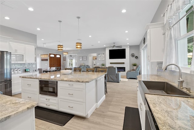 kitchen featuring white cabinetry, sink, hanging light fixtures, and stainless steel refrigerator