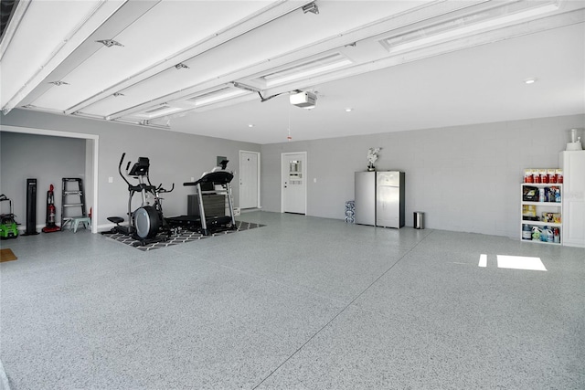 garage with a garage door opener and stainless steel refrigerator