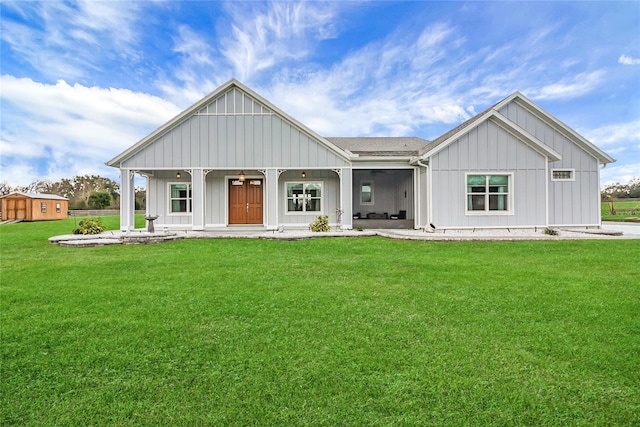 view of front facade featuring a porch, a storage unit, and a front lawn