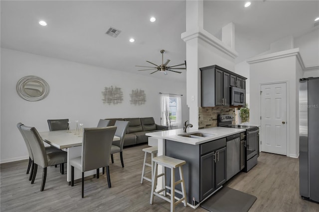 kitchen featuring appliances with stainless steel finishes, sink, a breakfast bar, kitchen peninsula, and tasteful backsplash