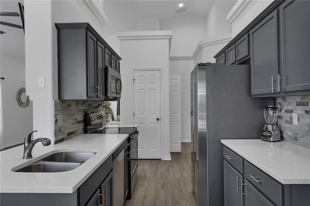 kitchen featuring light wood-type flooring, appliances with stainless steel finishes, sink, and gray cabinetry