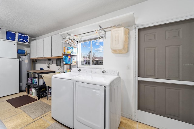 laundry area with a textured ceiling, cabinets, water heater, and washer and clothes dryer