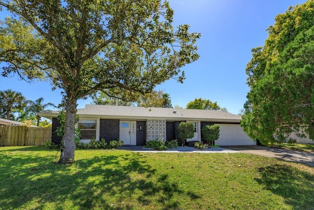 ranch-style home with a garage, a front lawn, driveway, and fence