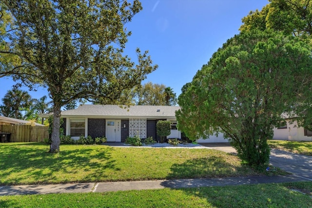 ranch-style home featuring driveway, a front lawn, and fence