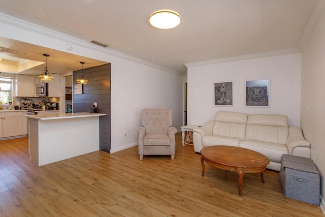 living room featuring visible vents, baseboards, light wood-style floors, and ornamental molding