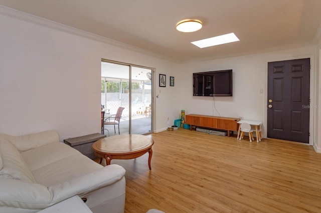 living room featuring light wood-style flooring, a skylight, crown molding, and baseboards