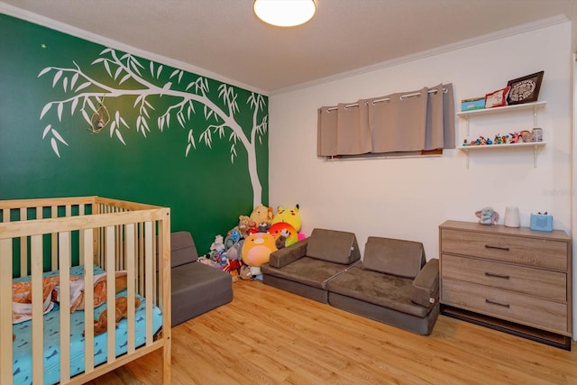 bedroom featuring a crib, wood finished floors, and ornamental molding