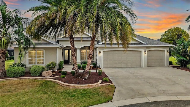 view of front of property featuring a garage, a front lawn, concrete driveway, and stucco siding