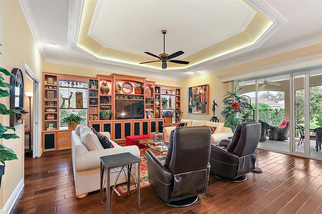 interior space with ceiling fan, crown molding, a raised ceiling, and dark wood finished floors